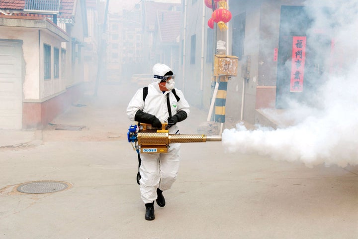 <strong>A Chinese volunteer wearing the protective clothing disinfects a street for prevention of the new coronavirus and pneumonia during the Chinese New Year or Spring Festival holiday in Dongxinzhuang Village, China.</strong>