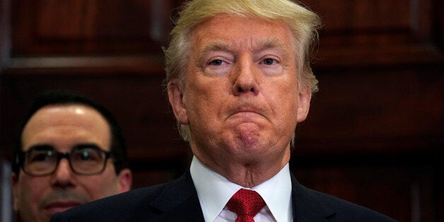 With Treasury Secretary Steve Mnuchin standing behind him, U.S. President Donald Trump listens to remarks before signing an executive order, making it easier for Americans to buy bare-bone health insurance plans and circumvent Obamacare rules at the White House in Washington, U.S., October 12, 2017. REUTERS/Kevin Lamarque