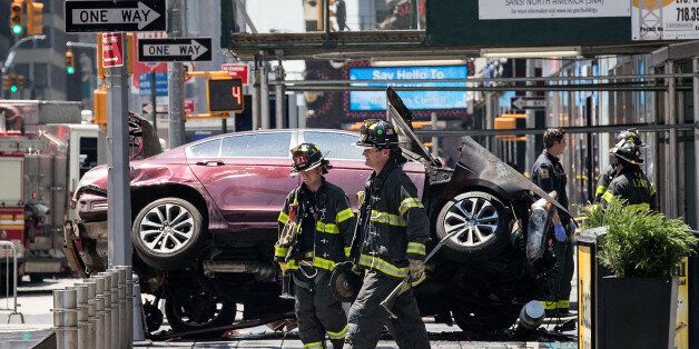 NEW YORK, NY - MAY 18: Firefighters walk past a wrecked car in the intersection of 45th and Broadway in Times Square, May 18, 2017 in New York City. According to reports there were multiple injuries and one fatality after the car plowed into a crowd of people. (Photo by Drew Angerer/Getty Images)