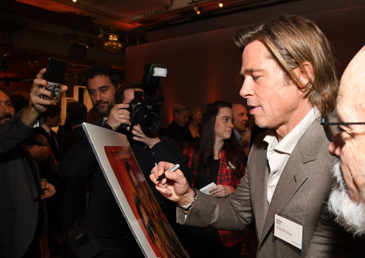 L'acteur américain Brad Pitt signe une affiche lors du dîner des nominés aux Oscars 2020, à Hollywood, le 27 janvier 2020.