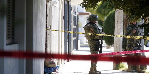 A soldier keeps watch outside the house where five people were shot dead during an operation to recapture the world's top drug lord Joaquin