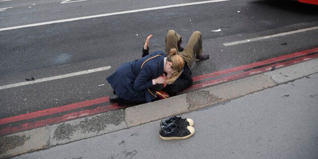 A woman assist an injured person after an incident on Westminster Bridge in London, March 22, 2017. REUTERS/Toby Melville