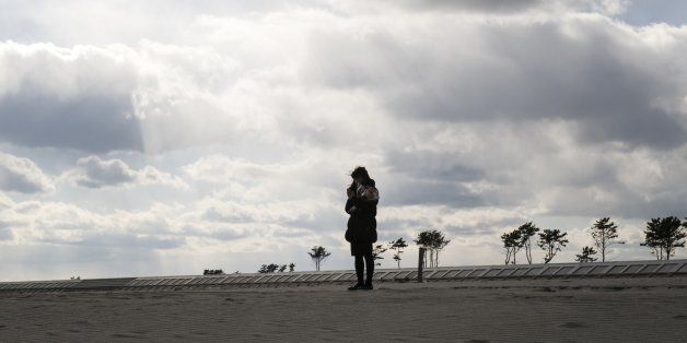 A young woman holding a bunch of flowers observes a moment of silence at 2:46 p.m. for the victims of massive earthquake and tsunami disaster in Arahama area, Miyagi prefecture at 11 March 2017. Six years have passed since the Great East Japan Earthquake and Tsunami disaster on 11 March 2011. Japanese National Police Agency report confirmed 15,893 deaths and 2,556 people missing across twenty prefectures. And 123,618 people are still living in temporary housing away from their home now. The Japanese government plans to lift evacuation orders in heavily contaminated areas around Fukushima Nuclear Power Plant complex by the end of March 2017, except some parts of the high radioactive area. (Photo by Yusuke Harada/NurPhoto via Getty Images)