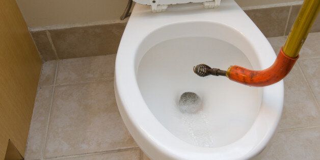 Plumber's snake unclogging a toilet in a residential home