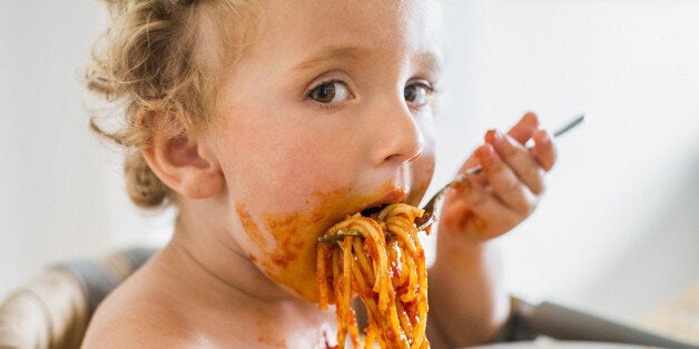 Young toddler boy eating messy pasta