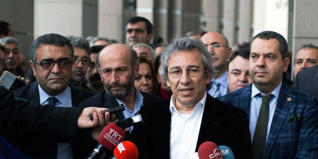 Can Dundar, the editor-in-chief of opposition newspaper Cumhuriyet, second right, and Erdem Gul, the paper's Ankara representative, second left, speak to the media outside a courthouse in Istanbul, Turkey, Thursday, Nov. 26, 2015. Turkey's Anadolu state-run news agency says a prosecutor has demanded that Dundar be jailed on charges of terror propaganda and for revealing state secrets along with Gul, when the Cumhuriyet paper published what it said were images of Turkish trucks carrying ammunitio