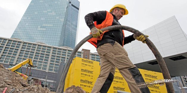 A worker is busy in front of the new headquarters of the European Central Bank during a media tour at the construction site in Frankfurt, Germany, Tuesday, Oct. 21, 2014. The ECB is supposed to move into the building by the end of 2014. (AP Photo/Jens Meyer)