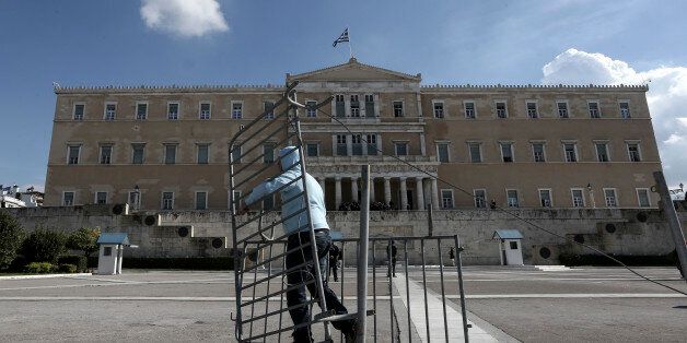 Following instructions from Greece's new left-wing public order minister, a worker removes crowd barriers that since early in the financial crisis screened off the Unknown Soldier's monument in front of Parliament in Athens, Wednesday, Jan. 28, 2015. The spot was a focal point for often violent anti-austerity protests. Greece's radical new government on Wednesday signaled the country would backtrack or scrap a series of budget measures its eurozone creditor nations had demanded in exchange for bailout loans. (AP Photo/InTime News, Kostas Baltas) GREECE OUT
