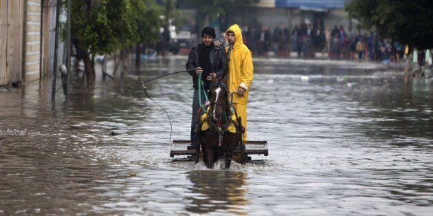 Palestinian men in a horse cart make their way through a flooded street during heavy rains in Gaza City on November 27, 2014 as a fierce winter storm which has been battering the region for the past four days. AFP PHOTO /MAHMUD HAMS (Photo credit should read MAHMUD HAMS/AFP/Getty Images)