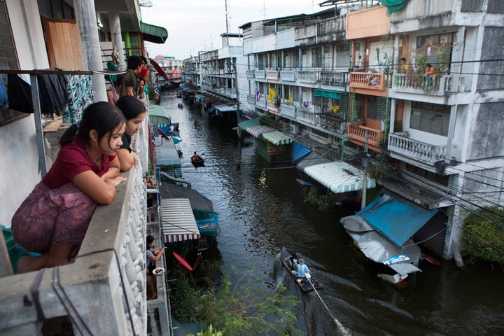 Bangkok residents look down at a flooded street where boats have become the main mode of transport in 2012.