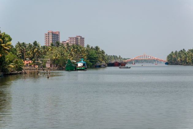 Mata Amritanandamayi's high-rise building ashram beside a water canal and between palm trees in the middle...