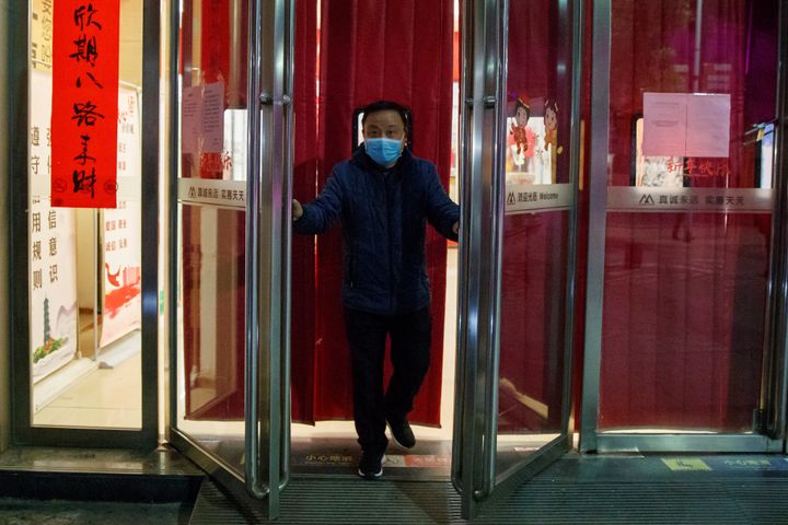 A man wearing a face mask closes a supermarket in Jiujiang, Jiangxi province, China, as the country is hit by an outbreak of a new coronavirus, February 1, 2020. REUTERS/Thomas Peter