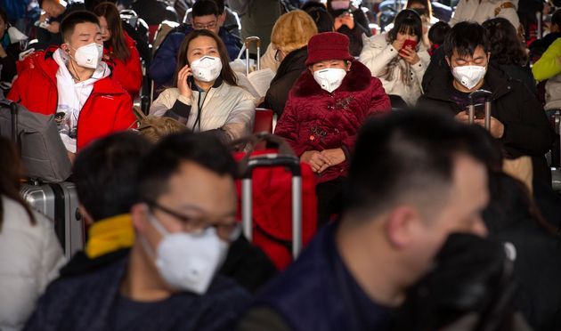Des voyageurs portent des masques de protection à la gare ferroviaire de Pékin, le 21 janvier....