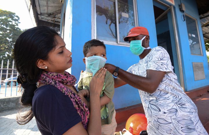A man wearing a surgical mask makes a child wear one outside the government general hospital where a student who had been in Wuhan is kept in isolation in Thrissur, Kerala, Jan. 30, 2020.