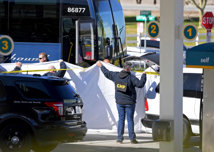 Coroner's officials work behind a drape to remove the body of a person who was killed when a gunman opened fire aboard a pack