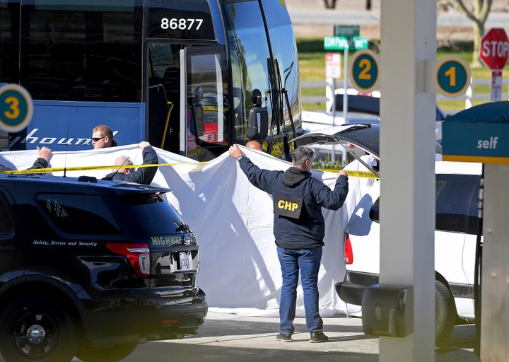 Coroner's officials work behind a drape to remove the body of a person who was killed when a gunman opened fire aboard a packed Greyhound bus. Five others were wounded.