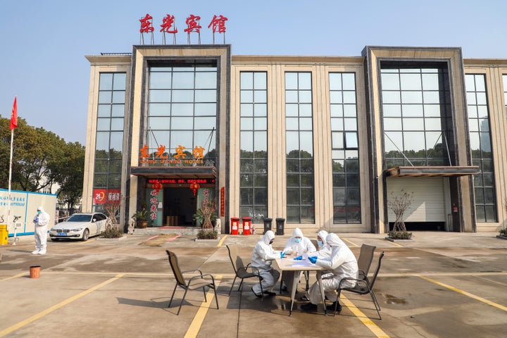 WUHAN, CHINA - FEBRUARY 03 2020: People in overalls talk at a table outside a hotel accommodating isolated people in Wuhan in central China's Hubei province Monday, Feb. 03, 2020.