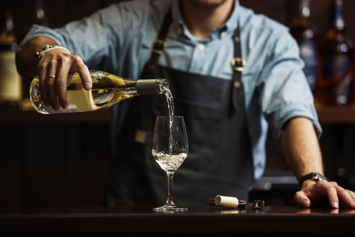 Ενας sommelier σερβίρει λευκό κρασί.