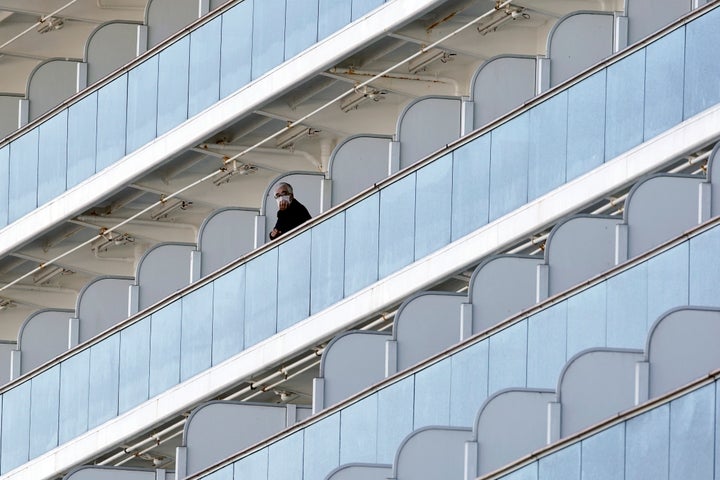 A passenger stands outside on the balcony of the cruise ship Diamond Princess anchored at the Yokohama Port on Feb. 6, 2020, in Yokohama, near Tokyo. 