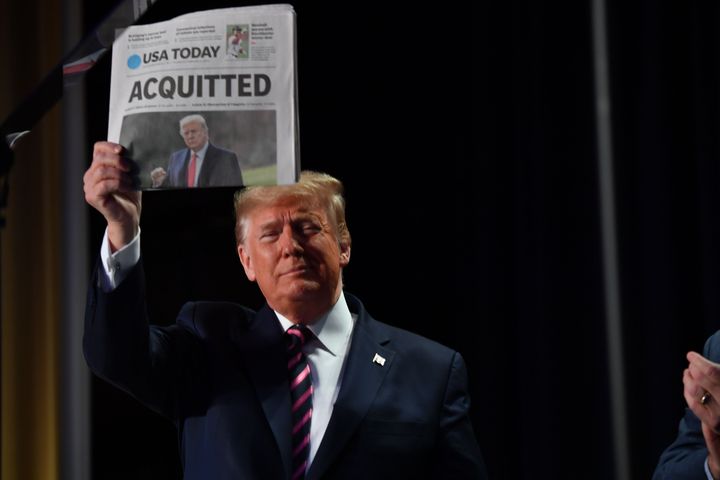 US President Donald Trump holds up a newspaper that displays a headline "Acquitted" as he arrives to speak at the 68th annual National Prayer Breakfast on February 6, 2020, in Washington, D.C. 