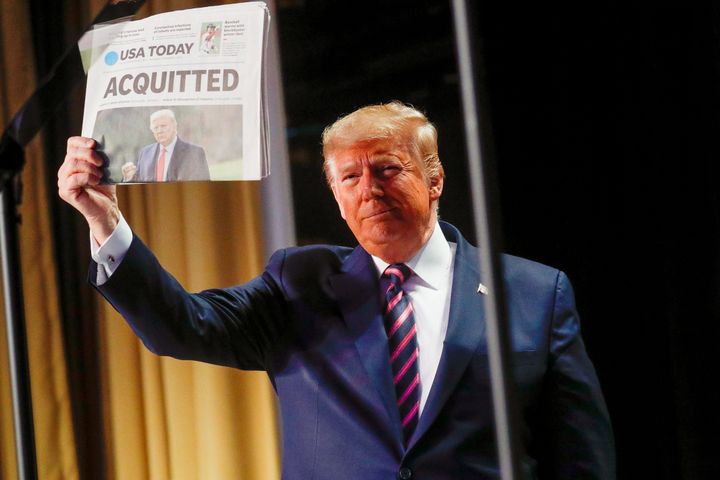 President Donald Trump holds up a copy of USA Today showing news of his acquittal in the Senate impeachment trial, as he arrives to address the National Prayer Breakfast in Washington on Feb. 6, 2020.