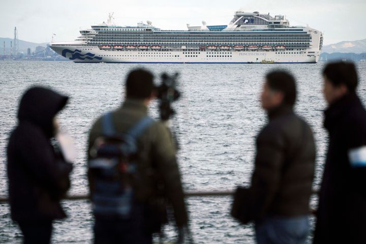 A TV crew film a cruise ship Diamond Princess anchoring off the Yokohama Port Tuesday, Feb. 4, 2020, in Yokohama, near Tokyo. Japanese health officials are conducting extensive medical checks on all 3,700 passengers and crew of the cruise ship that returned to the country after one passenger tested positive for the new coronavirus. (AP Photo/Eugene Hoshiko)
