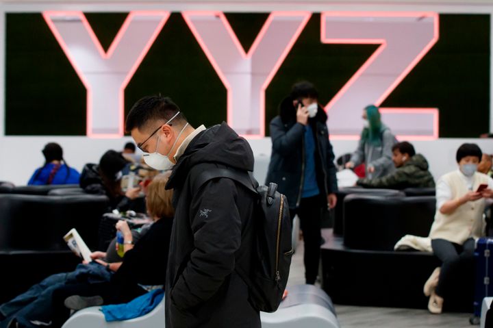 Travellers are seen wearing masks at the international arrivals area at Toronto Pearson Airport on Jan. 26, 2020.