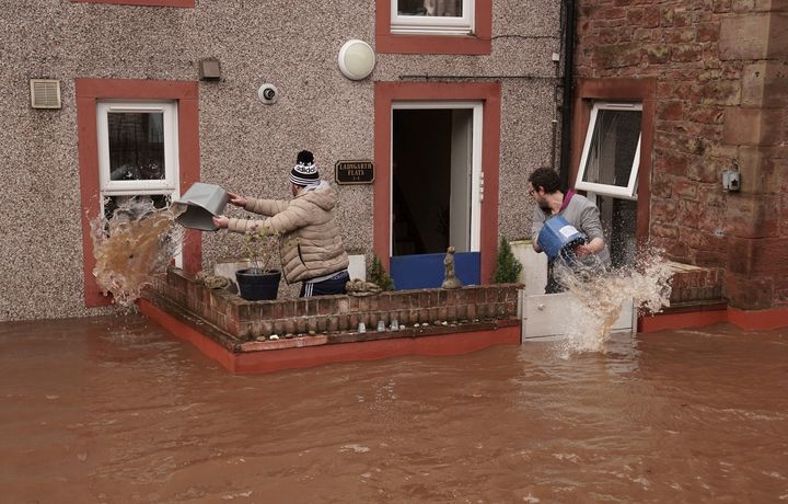 Men try to control the flow of flood water, outside a property, in Appleby-in-Westmorland, in Cumbria.
