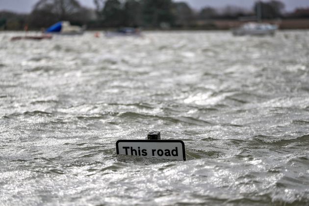 A street sign is seen under flood water in Bosham caused by the high tide, in England, Monday, Feb. 10, 2020. Storm Ciara battered the U.K. and northern Europe with hurricane-force winds and heavy rains Sunday, halting flights and trains and producing heaving seas that closed down ports. Propelled by the fierce winds, a British Airways plane was thought to have made the fastest New York-to-London flight by a conventional airliner. (Steve Parsons/PA via AP)