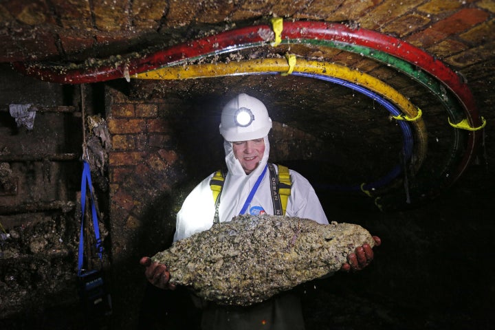 Tim Henderson, a "flusher" or trunk sewer technician holds a "fatberg" as he works in the intersection of the Regent Street and Victoria sewer in London on December 11, 2014.&nbsp;