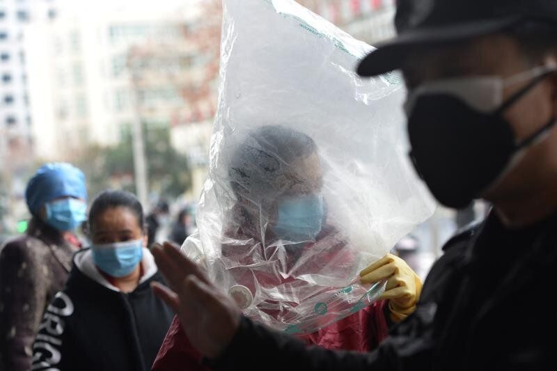 Una mujer se protege con una máscara y hasta con una bolsa en la provincia de Hubei