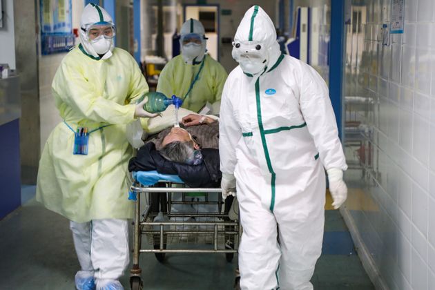 Medical workers in protective suits move a patient in an isolated ward of a Wuhan, China, hospital on Feb. 6, 2020.