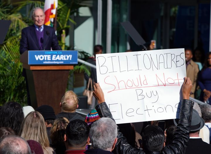 A protester holds up a sign as presidential candidate Mike Bloomberg speaks at a campaign rally in Compton, California, on Feb. 3.