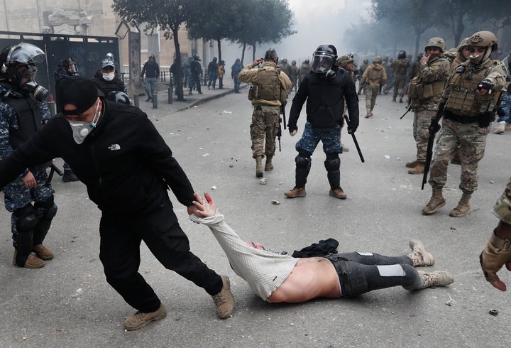 A Lebanese security officer drags an anti-government protester, who was clashing with riot police during a protest, in downto