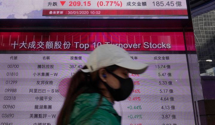 A woman walks past a bank electronic board showing the Hong Kong share index at Hong Kong Stock Exchange Thurs. Jan. 30, 2020.