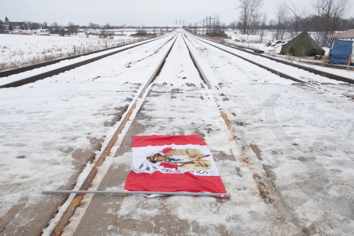 A Canadian maple leaf flag with native symbols on it lays on the train tracks in Tyendinaga Mohawk Territory, near Belleville, Ont., on Tuesday, Feb. 11, 2020.