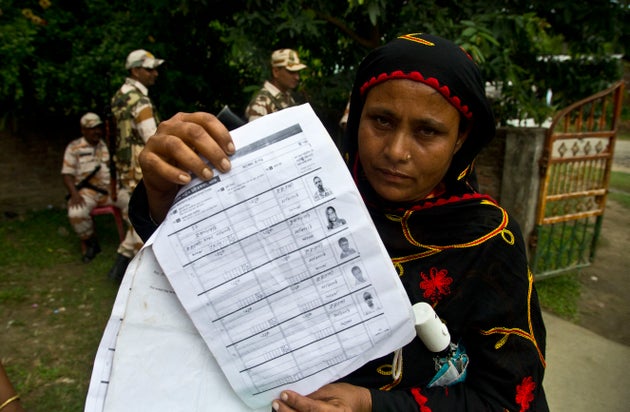 A woman displays a document that shows inclusion of her name in the final list of the National Register...