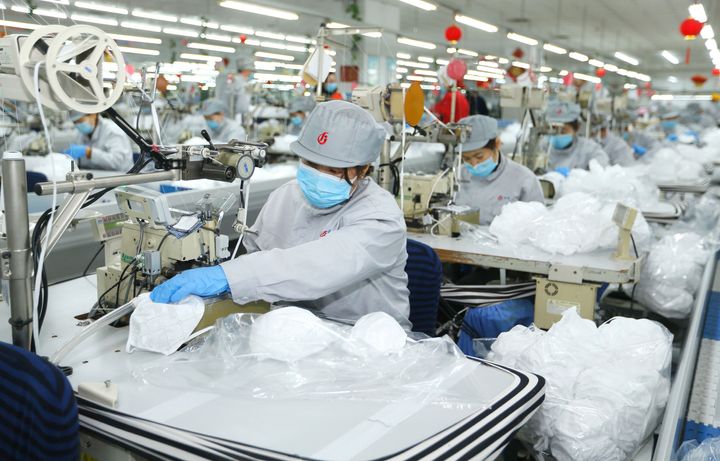 In this photo released by Xinhua News Agency, workers produce face masks in the workshop of a textile company in Jimo District of Qingdao in eastern China's Shandong Province on Wednesday, Feb. 12, 2020.