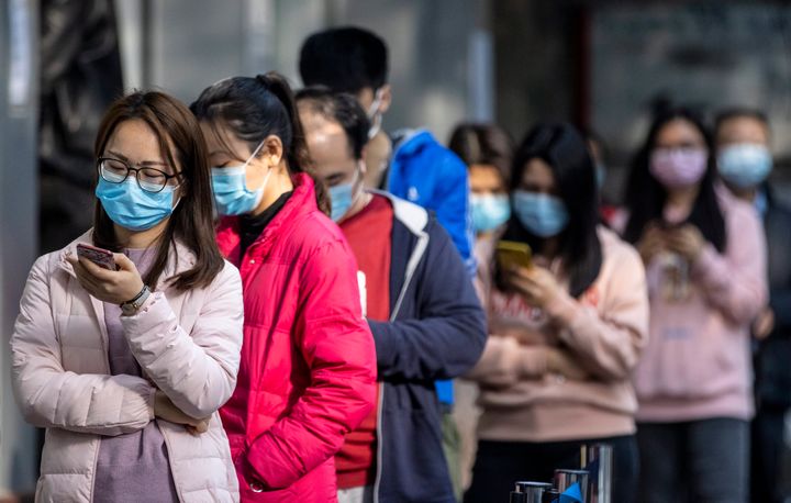 People wait in line outside a pharmacy in Guangzhou, China, on Thursday after winning a lottery to buy protective masks. Senior Chinese officials have been urging workers to return to their jobs amid the coronavirus outbreak. 