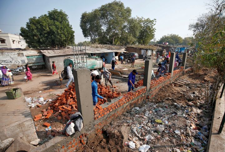 Construction workers build a wall along a slum area along a route that U.S. President Donald Trump and Prime Minister Narendra Modi will be taking during Trump's visit later this month, in Ahmedabad.