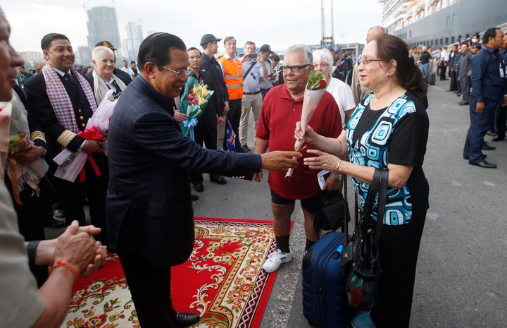 2月14日、カンボジア南部シアヌークビルに入港したウエステルダム号から下船した乗客にバラの花束を手渡すフン・セン首相