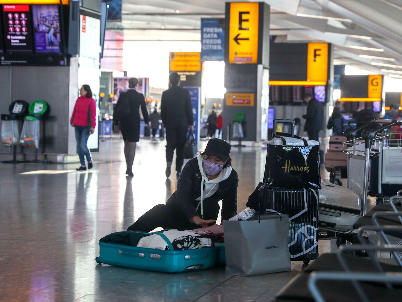 A woman wearing a face mask packs her suitcase in the departures area of Terminal 5 at Heathrow Airport, after it was announced British Airways had suspended all services to and from China.