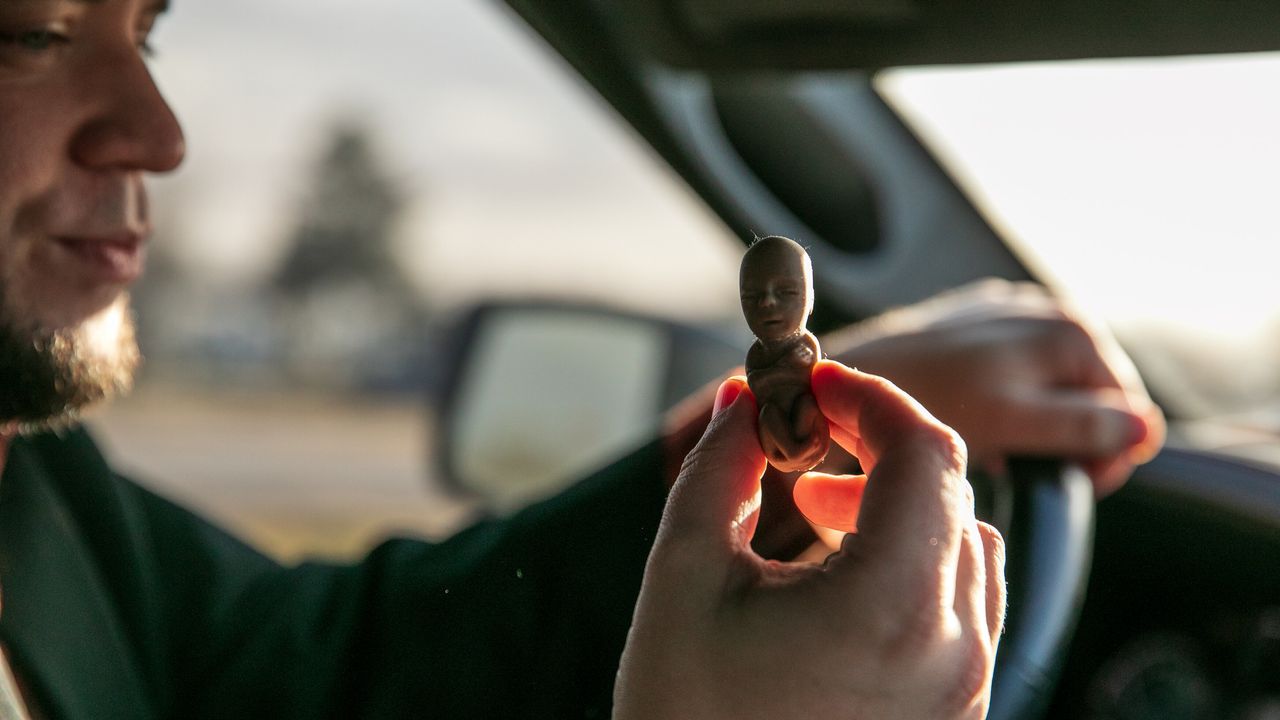 Mark Lee Dickson holds one of the plastic "fetal models" in the cab of his truck.