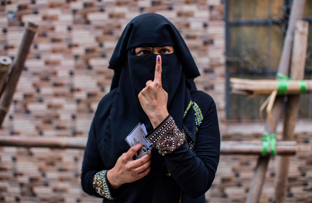 Μία γυναίκα από την Ινδία, δείχνει το δάχτυλο της πάνω στο οποίο υπάρχει ανεξίτηλο μελάνι, έξω από το εκλογικό τμήμα, στο οποίο μόλις έχει ψηφίσει, στο Νέο Δελχί, στις 8 Φεβρουαρίου.