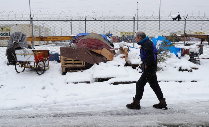 Kevin Shepherd walks back to the tent where he lives as snow falls in Seattle on Feb. 11, 2019. Shepherd, who works as a musi
