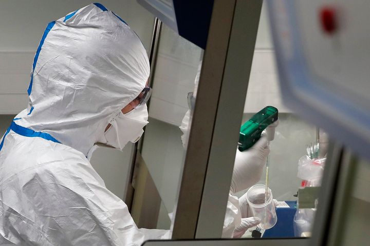 French lab scientist in hazmat gear inserting liquid in test tube manipulates potentially infected patient samples at Pasteur Institute in Paris, Thursday, Feb. 6, 2020. Scientists at the Pasteur Institute developed and shared a quick test for the new virus that is spreading worldwide, and are using genetic information about the coronavirus to develop a potential vaccine and treatments. (AP Photo/Francois Mori)