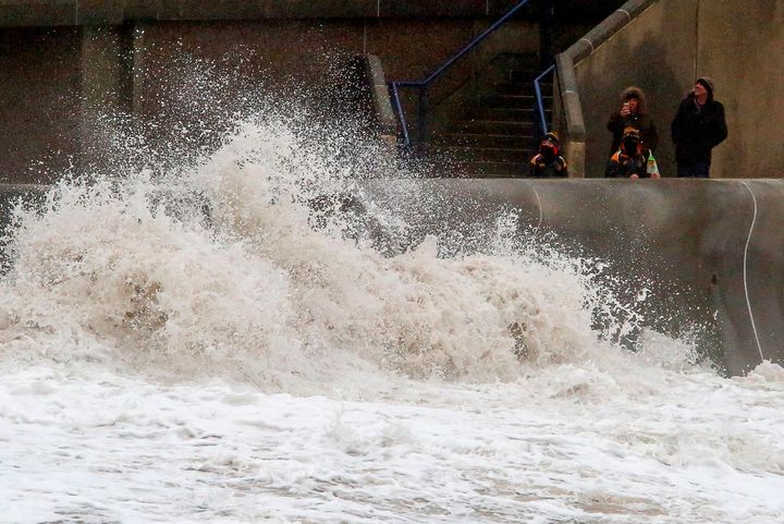Bystanders take photographs as huge waves crash against the sea wall at Porthcawl, south Wales.