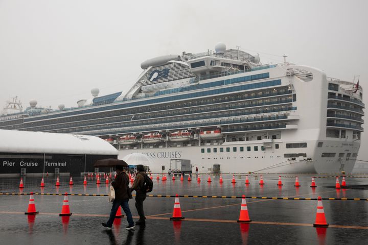 Visitors walk past the quarantined Diamond Princess cruise ship in Yokohama, near Tokyo. Americans who have not testes positive for the virus will be flown back home on chartered flights Sunday, but will face another two-week quarantine.