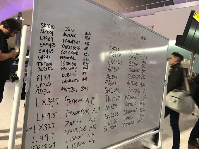 Whiteboards displaying handwritten flight numbers and destinations at Heathrow after the airport experienced technical difficulties.