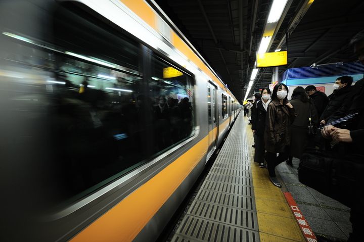 マスクを着けて駅のホームを歩く人たち＝2月11日、東京都内